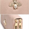 Alt Text: Close-up of gold bee and pearl embellishment on wallet