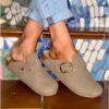 Woman wearing faux suede mocha mules styled with rolled-up jeans on decorative stairs