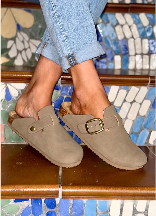 Woman wearing faux suede mocha mules styled with rolled-up jeans on decorative stairs