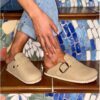 Woman wearing faux suede stone mules styled with rolled jeans on mosaic stairs
