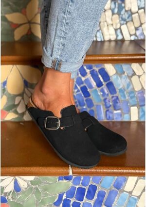 Woman wearing black faux suede mules with silver buckle and rolled jeans