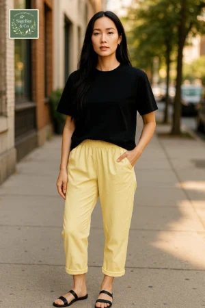 Woman wearing a black t-shirt with yellow cropped trousers from SageBay & Co on a sunny city street