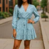 Woman wearing a blue floral long sleeve mini dress with tie waist standing in the street