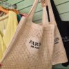 Cream crochet shoulder bag with “Paris Milano” embroidery hanging in a boutique